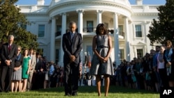 President Barack Obama, first lady Michelle Obama, and others, pause on the South Lawn of the White House in Washington, Sept. 11, 2015, as they observe a moment of silence to mark the 14th anniversary of the 9/11 attacks. 