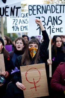 A woman raises her fist as she and thousands of others protest against domestic violence, in Paris, Nov, 23, 2019.