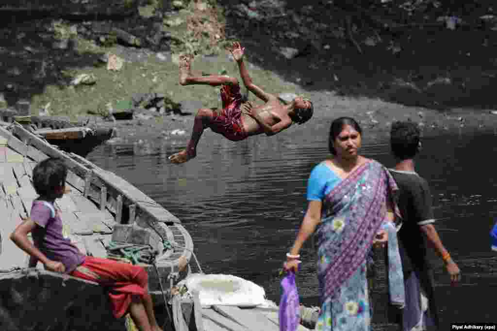 A boy dives into the polluted Adi Ganga River to collect coins, next to Kalighat temple, in Calcutta, eastern India.