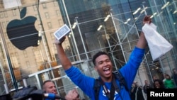 One of the first customers to purchase the Apple iPhone 5S celebrates after exiting the Apple Retail Store on Fifth Avenue in Manhattan, New York, Sept. 20, 2013.