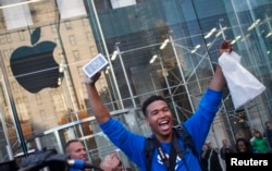 One of the first customers to purchase the Apple iPhone 5S celebrates after exiting the Apple Retail Store on Fifth Avenue in Manhattan, New York, Sept. 20, 2013.