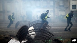 Demonstrators run away during clashes Saturday, Dec. 8, 2018 in Paris. Crowds of yellow-vested protesters angry at President Emmanuel Macron and France's high taxes tried to converge on the presidential palace Saturday, some scuffling with police firing t