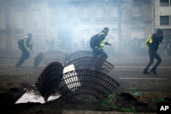 Demonstrators run away during clashes Saturday, Dec. 8, 2018 in Paris. Crowds of yellow-vested protesters angry at President Emmanuel Macron and France's high taxes tried to converge on the presidential palace Saturday, some scuffling with police firing tear gas, amid exceptional security measures aimed at preventing a repeat of last week's rioting.