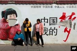 2014年3月2日昆明火车站外“中国梦”宣传海报下的乘客