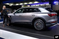 FILE - A model holds the power cable that charges the new electric Audi e-tron Quatro, displayed at the e-Motor show in Beirut, Lebanon, April 11, 2019.