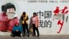 Passengers wait in front of a broken propaganda poster featuring "the China Dream" outside the Kunming Railway Station in Kunming, in western China's Yunnan province, Sunday, March 2, 2014.