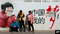 Passengers wait in front of a broken propaganda poster featuring "the China Dream" outside the Kunming Railway Station in Kunming, in western China's Yunnan province, March 2, 2014.