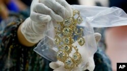 FILE - In this Nov. 24, 2015, file photo, a Bureau of Customs appraiser shows to the media a set of jewelry from Roumeliotes Collection, one of three sets of the Marcos Jewelry Collection, during appraisal at the Central Bank of the Philippines, in Manila, Philippines.