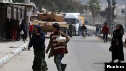 FILE - People walk in the center of Afrin, Syria, March 24, 2018. 