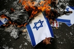 Seorang demonstran membakar mockup bendera Israel saat protes mengutuk keputusan Washington untuk mengakui Yerusalem sebagai ibu kota Israel, di luar kedutaan AS di Jakarta, 15 Desember 2017. (Foto: REUTERS/Beawiharta)