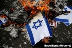 Seorang demonstran membakar mockup bendera Israel saat protes mengutuk keputusan Washington untuk mengakui Yerusalem sebagai ibu kota Israel, di luar kedutaan AS di Jakarta, 15 Desember 2017. (Foto: REUTERS/Beawiharta)