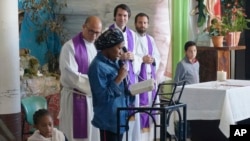 Eslande, a migrant mother from Haiti, reads the Gospel in Creole during Mass celebrated in the Casa del Migrante shelter by three Jesuit priests, from left, the Revs. Flavio Bravo, Louie Hotop and Brian Strassburger, in Reynosa, Mexico, on Dec. 15, 2022.