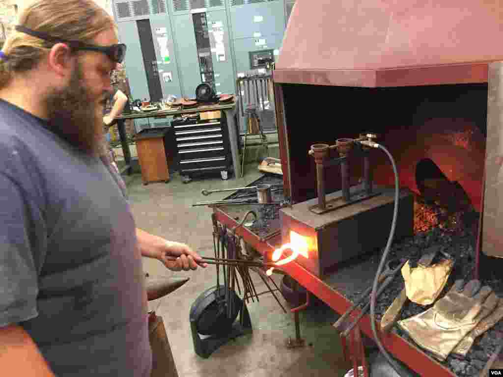 American College of the Building Arts student Jeremiah Price heats up an iron door pull, Charleston, S.C., Sept. 17, 2019. (J. Taboh/VOA News)