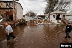 FILE - Men walk through flooding left by the storm surge of Superstorm Sandy in the New Dorp Beach neighborhood of the Staten Island borough of New York, Nov. 1, 2012.