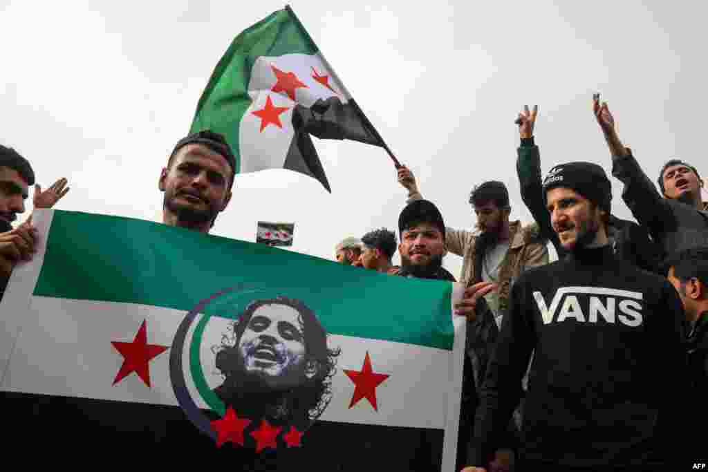 Syrians wave the opposition flag bearing the portrait of late rebel fighter and famous chanter Abdel-Basset al-Sarout in Arbil, the capital of Iraq's northern autonomous Kurdish region, on Dec. 8, 2024.