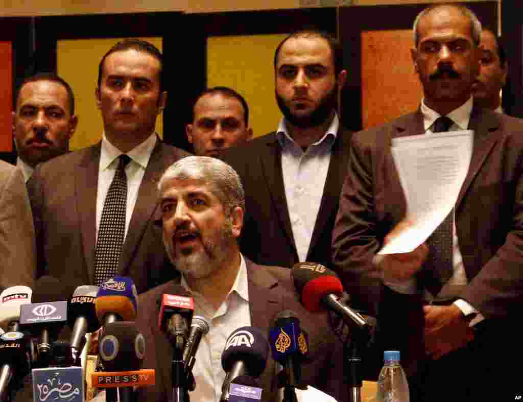 Hamas leader Khaled Mashaal holds a copy of the Hamas-Israel cease-fire agreement during a press conference in Cairo, Egypt, Wednesday, Nov. 21