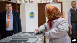 An elderly woman casts her vote at a polling station during presidential elections in Chisinau, Moldova, Oct. 30, 2016. 