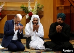 FILE - Muslim men pray for victims of the attack at Manchester Arena at a mosque in Manchester, May 23, 2017.