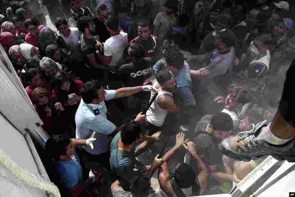 A policeman hits a migrant as police try to disperse hundreds of migrants during a registration procedure that was taking place at the stadium of Kos town, on the southeastern island of Kos, Greece, Aug. 11, 2015. 