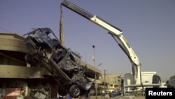 A burnt vehicle is removed from the site of a bomb attack that killed Shi'ite pilgrims making their way to a religious festival in Baghdad, Iraq, June 13, 2012.