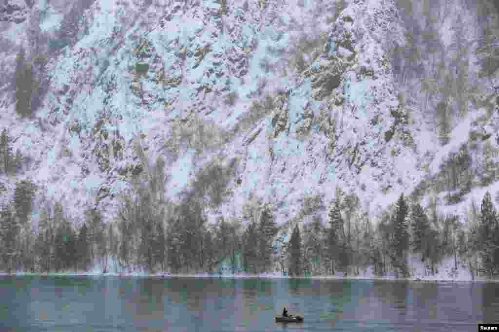 A man fishes from a boat on the Yenisei River outside the Siberian city of Krasnoyarsk, Russia.