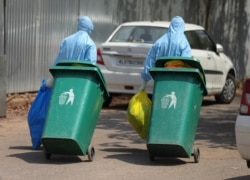 Indian workers walk with garbage after cleaning an isolation ward at a hospital for observing people suspected to have a new coronavirus infection in Kochi, Kerala state, Feb.4, 2020.