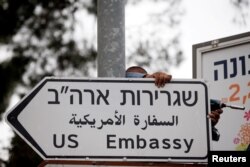 FILE - A worker hangs a road sign directing traffic to the U.S. Embassy, in the area of the U.S. Consulate, in Jerusalem, May 7, 2018.