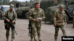 Menteri Pertahanan Ukraina Valery Heletey (tengah) berjalan bersama para tentara di markas sementara dekat kota Slovyansk (6/7).