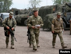 Newly appointed Ukrainian Defense Minister Valery Heletey, center, walks with troops at a temporary base near the city of Slovyansk, July 6, 2014.