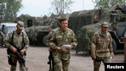 新任乌克兰国防部长谢列特（中）在斯洛文斯克附近的一处临时基地与军人走在一起。（2014年7月6日）
