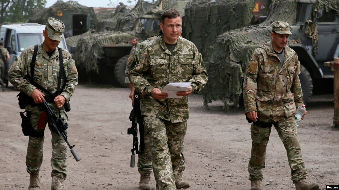 Menteri Pertahanan Ukraina Valery Heletey (tengah) berjalan bersama para tentara di markas sementara dekat kota Slovyansk (6/7).