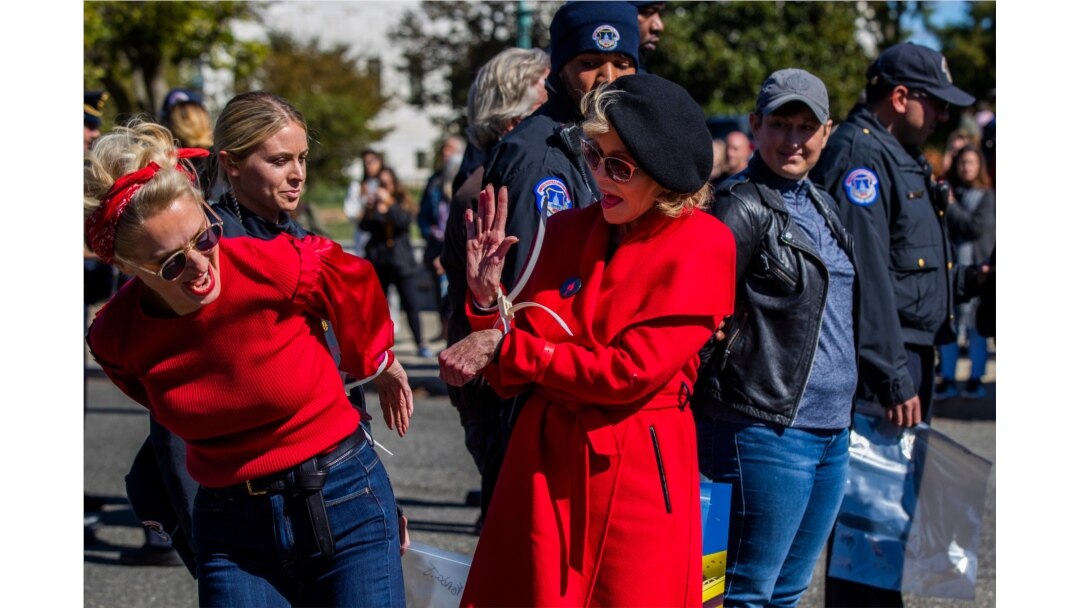 Actress Jane Fonda, center, gives fellow activist a high five after they were arrested during a rally on Capitol Hill in Washington, Oct. 18, 2019.