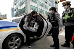 A student gets off a police vehicle which carried her to a high school to arrive in time for a college entrance exam in Seoul, South Korea, Thursday, Nov. 18, 2021.