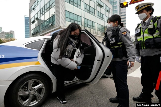 A student gets off a police vehicle which carried her to a high school to arrive in time for a college entrance exam in Seoul, South Korea, Thursday, Nov. 18, 2021.