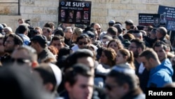 A mourner holds pictures of the victims of an attack on a Paris grocery on Friday, during their joint funeral in Jerusalem, Jan. 13, 2015.