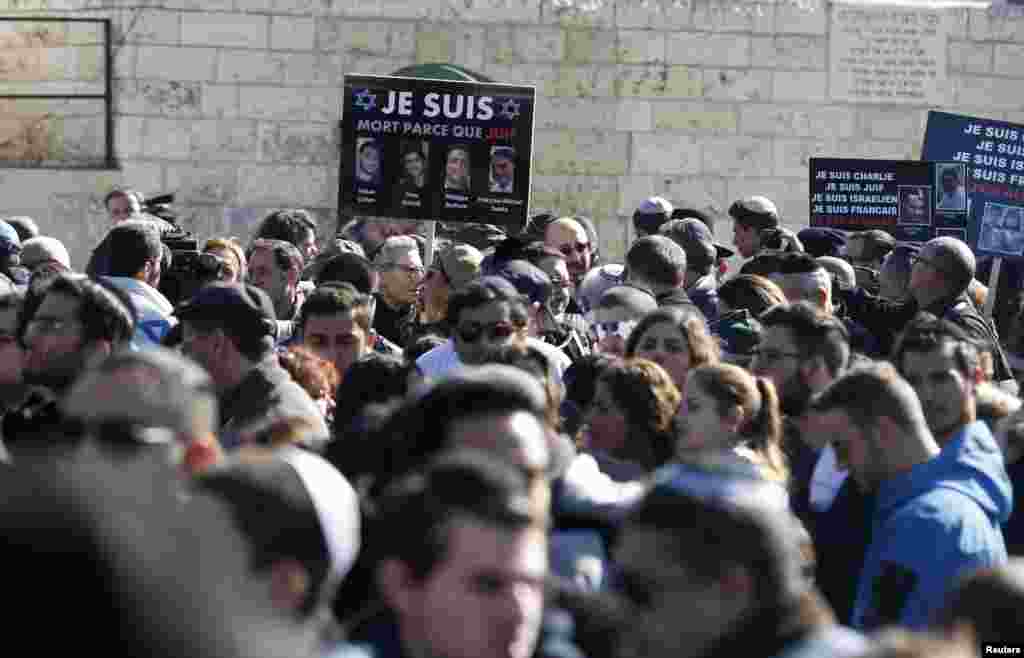 A mourner holds a placard with pictures of the victims of an attack on a Paris grocery on Friday, during their joint funeral in Jerusalem, Jan. 13, 2015.