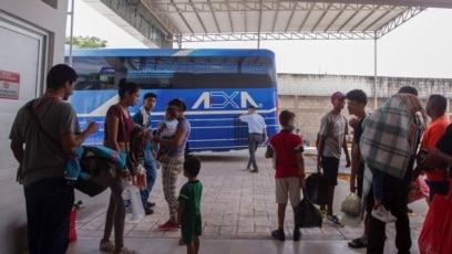 Migrantes que abandonaron una caravana después de recibir documentos para permanecer en México abordan un autobús en Huixtla el 10 dee junio de 2022.