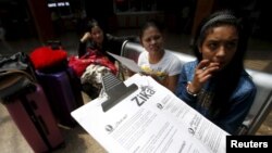 FILE - A Colombian health worker gives travellers information on how to prevent the spread of the Zika virus, at the main bus terminal in Bogota, Colombia, Jan. 31, 2016.