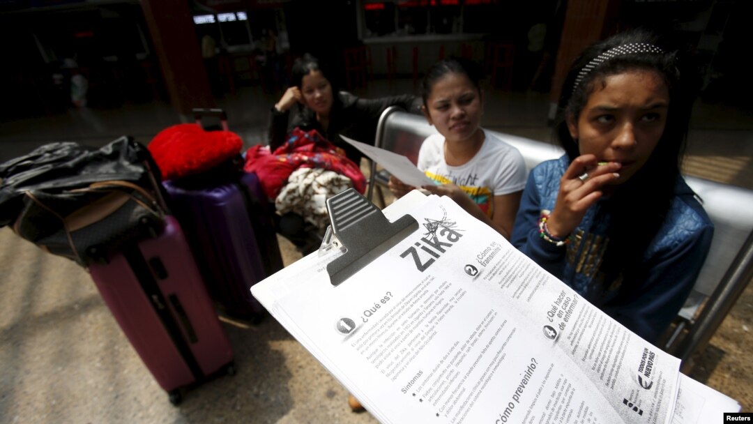 FILE - A Colombian health worker gives travellers information on how to prevent the spread of the Zika virus, at the main bus terminal in Bogota, Colombia, Jan. 31, 2016.