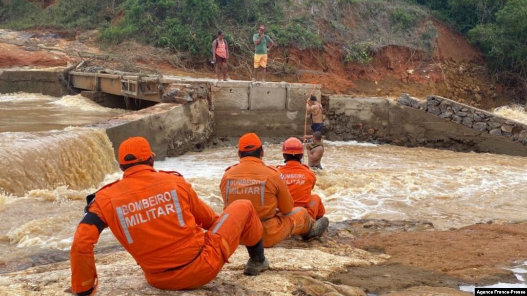  Firefighters help residents cross a river after the collapse of a bridge following heavy rains, in Itamaraju, south of Bahia State, Brazil, on Dec. 12, 2021. (Photo by Bahia State Fire Department / AFP)