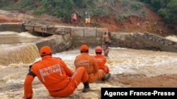  Firefighters help residents cross a river after the collapse of a bridge following heavy rains, in Itamaraju, south of Bahia State, Brazil, on Dec. 12, 2021. (Photo by Bahia State Fire Department / AFP)