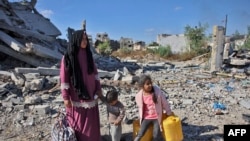 Una mujer palestina junto a sus hijos en la carretera de Salah al-Din, en el este de Gaza, después de ser obligada a huir de las operaciones militares israelíes en Beit Lahia, norte de la franja de Gaza, el 22 de octubre de 2024, en medio de la guerra entre Israel y Hamás.