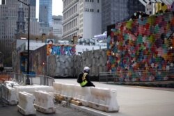A construction worker sits alone along an empty sidewalk near the World Trade Center in lower Manhattan during the outbreak of the coronavirus disease in New York City, New York, March 27, 2020.