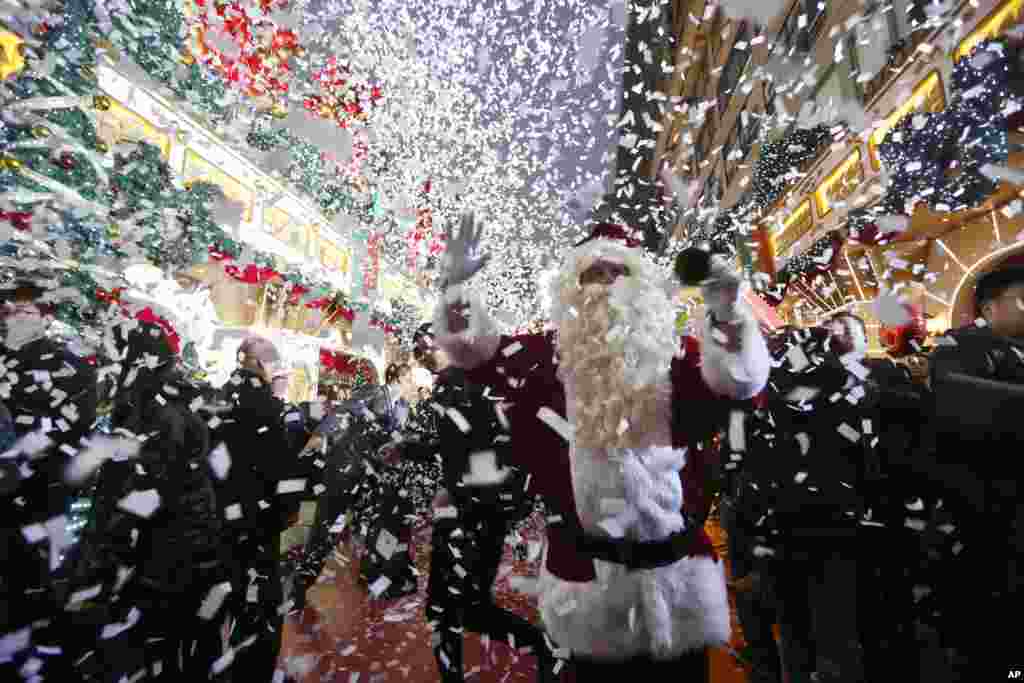 A staff member dressed as Santa Claus poses for a photo with Christmas decorations to celebrate the festival season at a shopping mall in Hong Kong, Dec. 23, 2013.