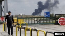 A member of Jordanian security walks near the main Jaber border crossing in Mafraq, Jordan, as smoke rises on the Syrian side after violence broke out near the border, April 2, 2015.