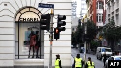 Limpiadores pasan al lado de una tienda Chanel en el distrito comercial central de Melbourne el 11 de mayo de 2020 cuando Australia comienza a aliviar sus restricciones contra el coronavirus COVID-19.