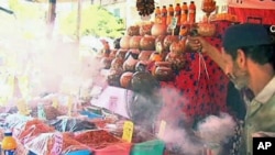 A man spreads incense smoke over the goods to ward off the evil eye, in the marketplace in Cairo, July 2011