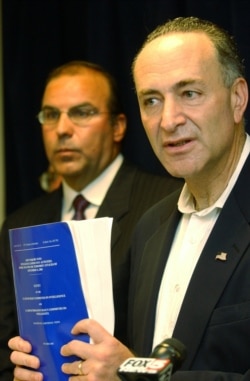 FILE - Sen. Charles Schumer, D-N.Y., right, is flanked by John D'Amato, an attorney for the victims of the Sept. 11, 2001, attacks, as he faces reporters in New York, July 27, 2003, with a copy of the government report on the attacks.