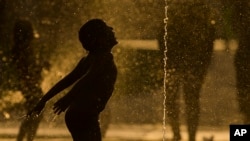 A child stays cool in a fountain beside Manzanares River in Madrid, Spain, Thursday, July 17, 2014.