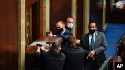 US Capitol Police with guns drawn stand near a barricaded door as a mob tries to break into the House Chamber at the US Capitol on Jan. 6, 2021, in Washington.